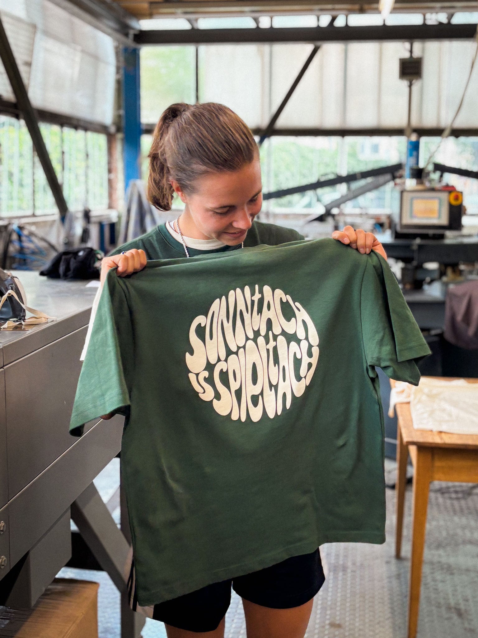 Meret Folten, Gründerin der Streetwear-Marke onside story, hält das erste per Siebdruck bedruckte "sonntach is spieltach" Shirt in den Händen.