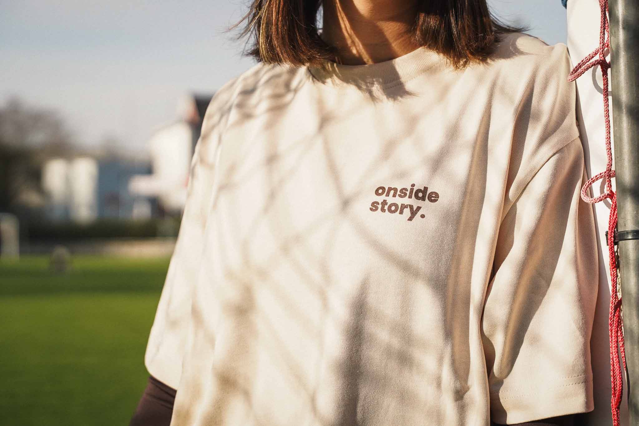 Nahaufnahme des Frontprints mit dem Logo "onside story" auf dem Shirt in Sand.