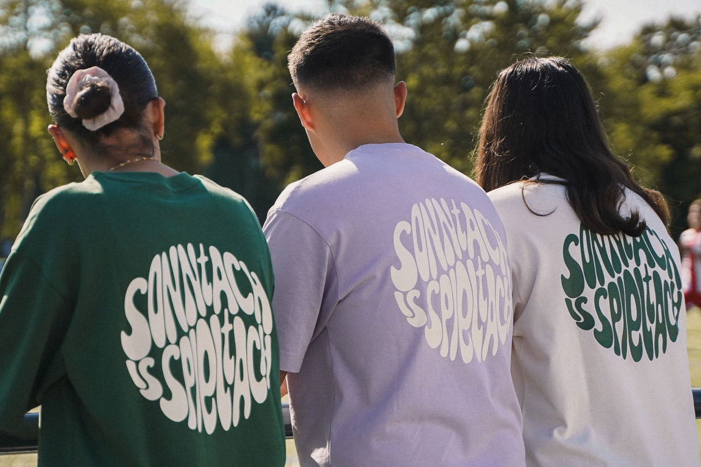 Drei Fußballfans stehen am Spielfeldrand und tragen das "sonntach is spieltach"-Shirt in Bottlegreen, Lavender und Cream der Fußball-Streetwear Brand onside story.